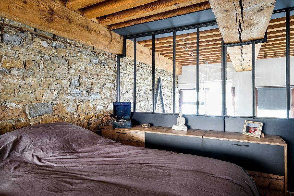 Bức tường đá thô mộc và dầm gỗ lộ thiên mang đến cái nhìn cực phong cách cho phòng ngủ nam giới độc thân này.