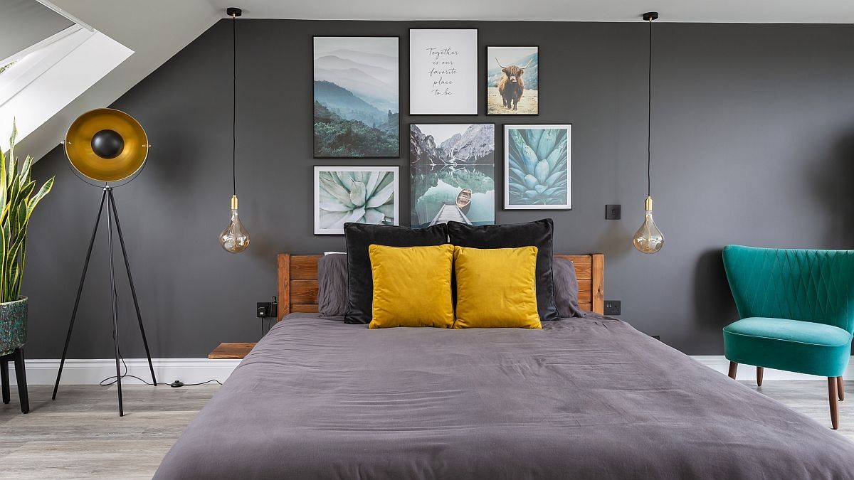 Gối nhấn và tác phẩm nghệ thuật trên tường đầu giường thêm màu sắc cho phòng ngủ độc thân tông màu xám chủ đạo.