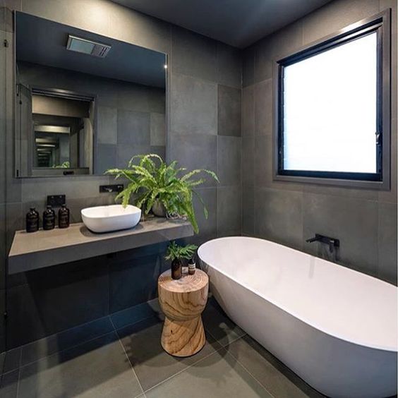 Trong nhà ống 4 tầng, tường và sàn phòng tắm đều được ốp gạch màu xám than tạo cảm giác sạch sẽ, giúp gia tăng chiều sâu cho căn phòng.