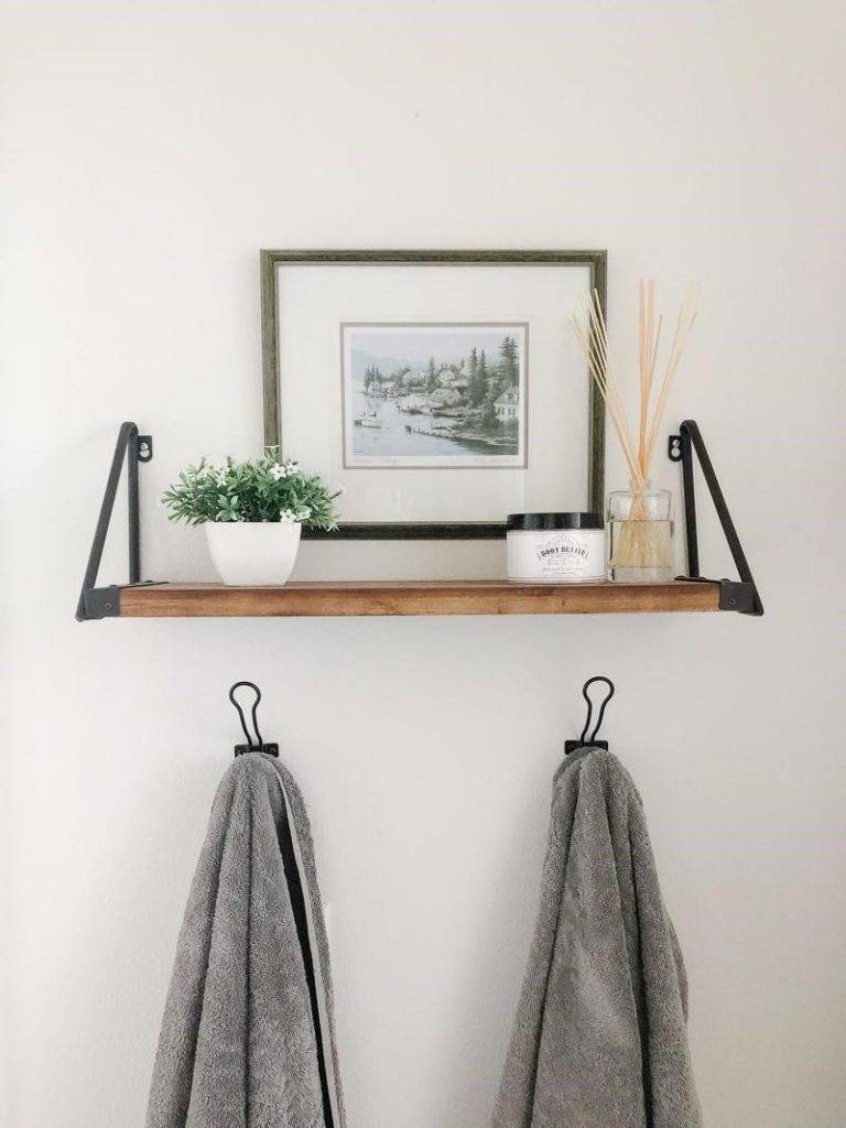Khung ảnh đen trắng kết hợp ăn ý với kệ gỗ gắn tường và móc treo khăn, tất cả hòa quyện tạo thành bức tường điểm nhấn cho phòng tắm.