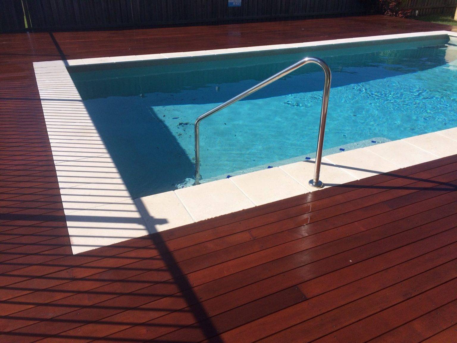 hồ bơi xanh trong với sàn bể bơi bằng gỗ màu nâu cánh gián