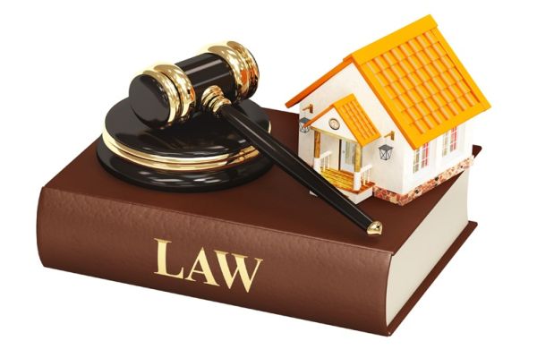 hình ảnh mô hình ngôi nhà, búa pháp luật đặt trên cuốn sách dày màu nâu, gáy in chữ law