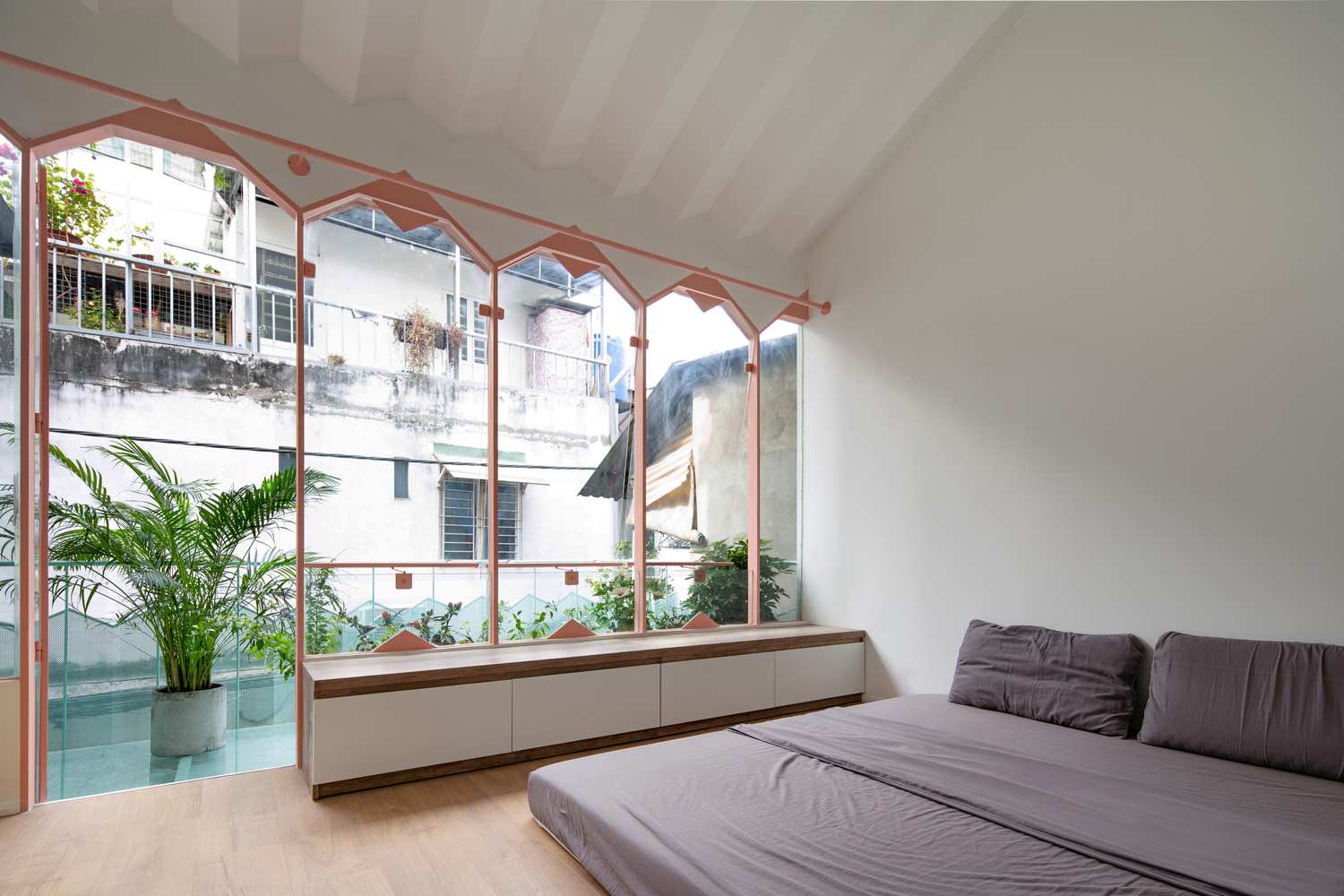 Hệ cửa sổ kính trong suốt với phần trên hình tam giác cho phép ánh sáng tự nhiên ngập tràn không gian phòng ngủ.