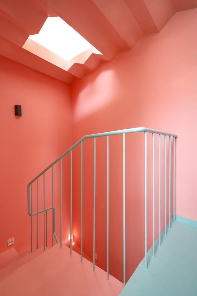 Cầu thang sơn màu hồng cam trẻ trung, tươi mới. Thiết kế cầu thang kết hợp giếng trời giúp lấy sáng tự nhiên, thông gió chéo hiệu quả.