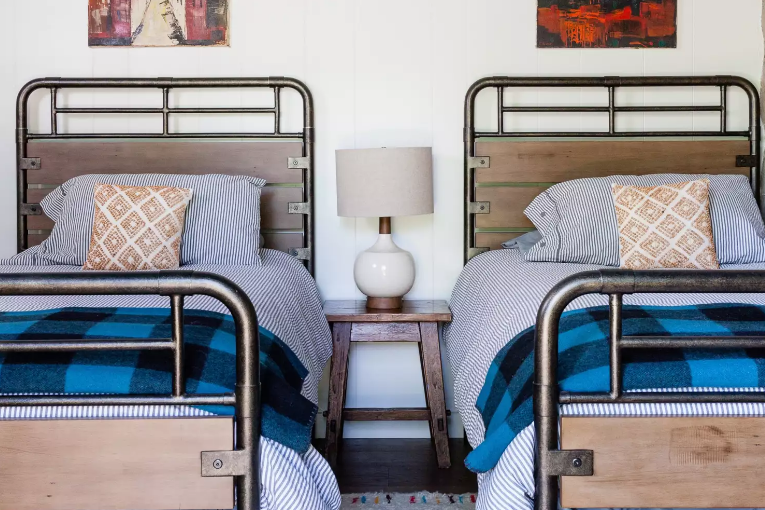 Trong phòng ngủ 2 giường đơn này, chăn kẻ sọc ở mỗi giường tạo điểm nhấn ấm áp, màu xanh lam sáng giúp căn phòng luôn tươi mới. 